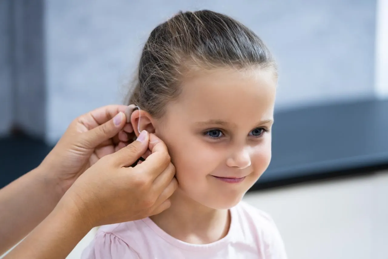 Hearing aid being fitted behind a young girl’s ear