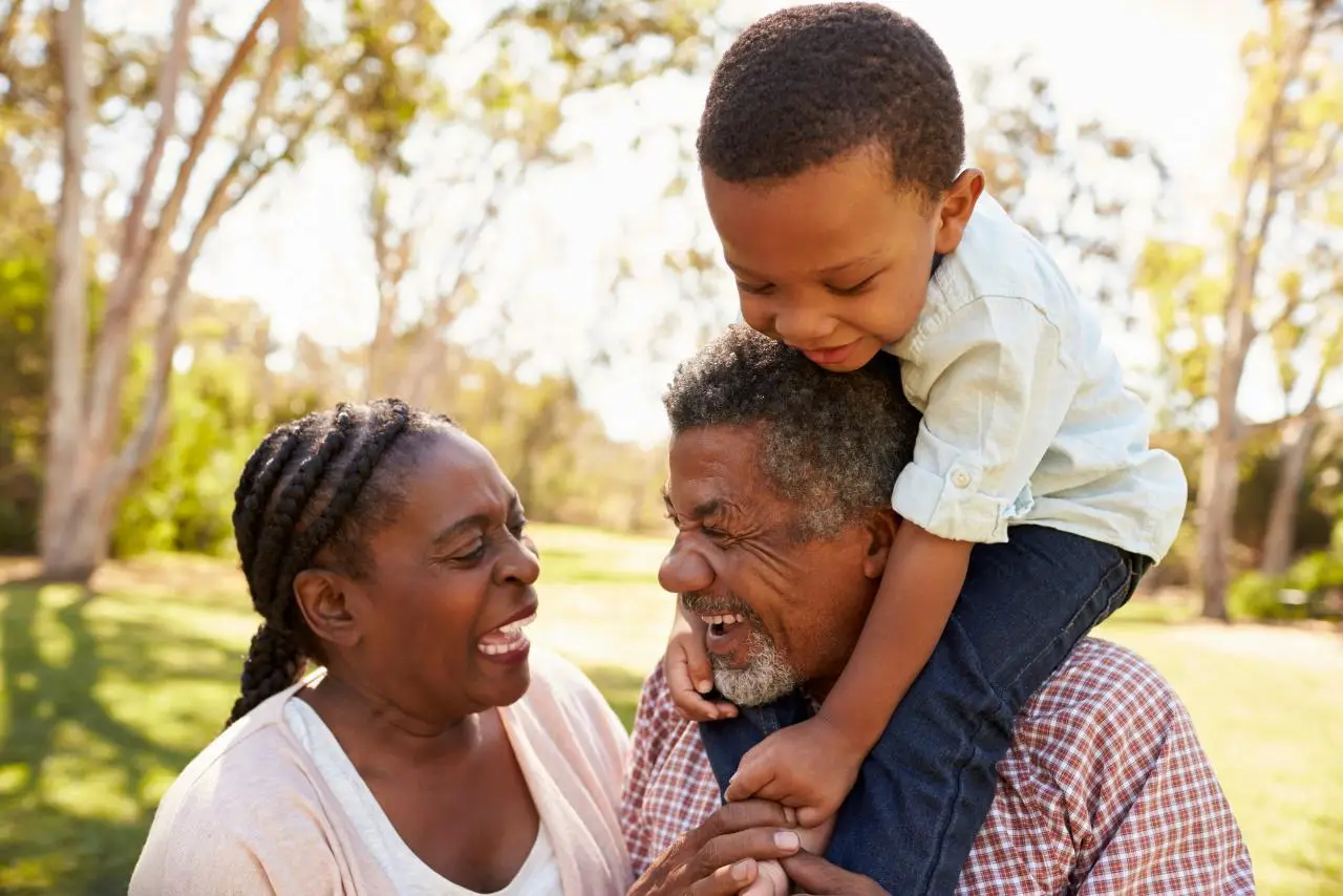 Older couple smiling with a grandchild on the grandfather’s shoulders